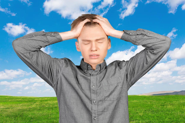 Jeune garçon qui se tient la tête à deux mains à cause du stress climatique, de l'éco anxiété, de la solastalgie